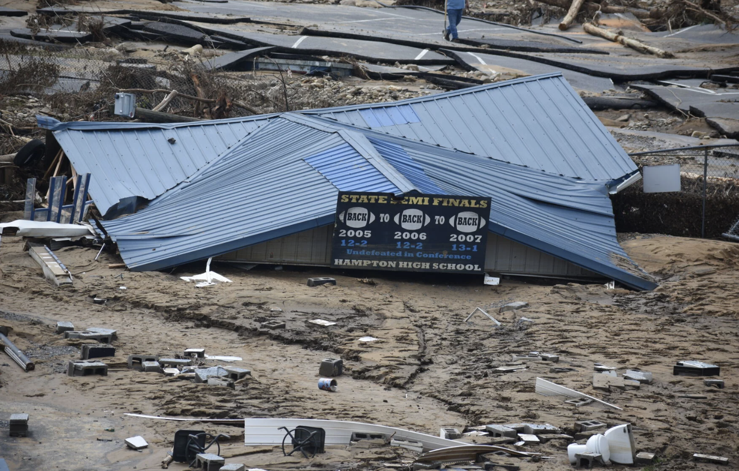 A metal roof from a building sits on the ground surrounded by other flood debris