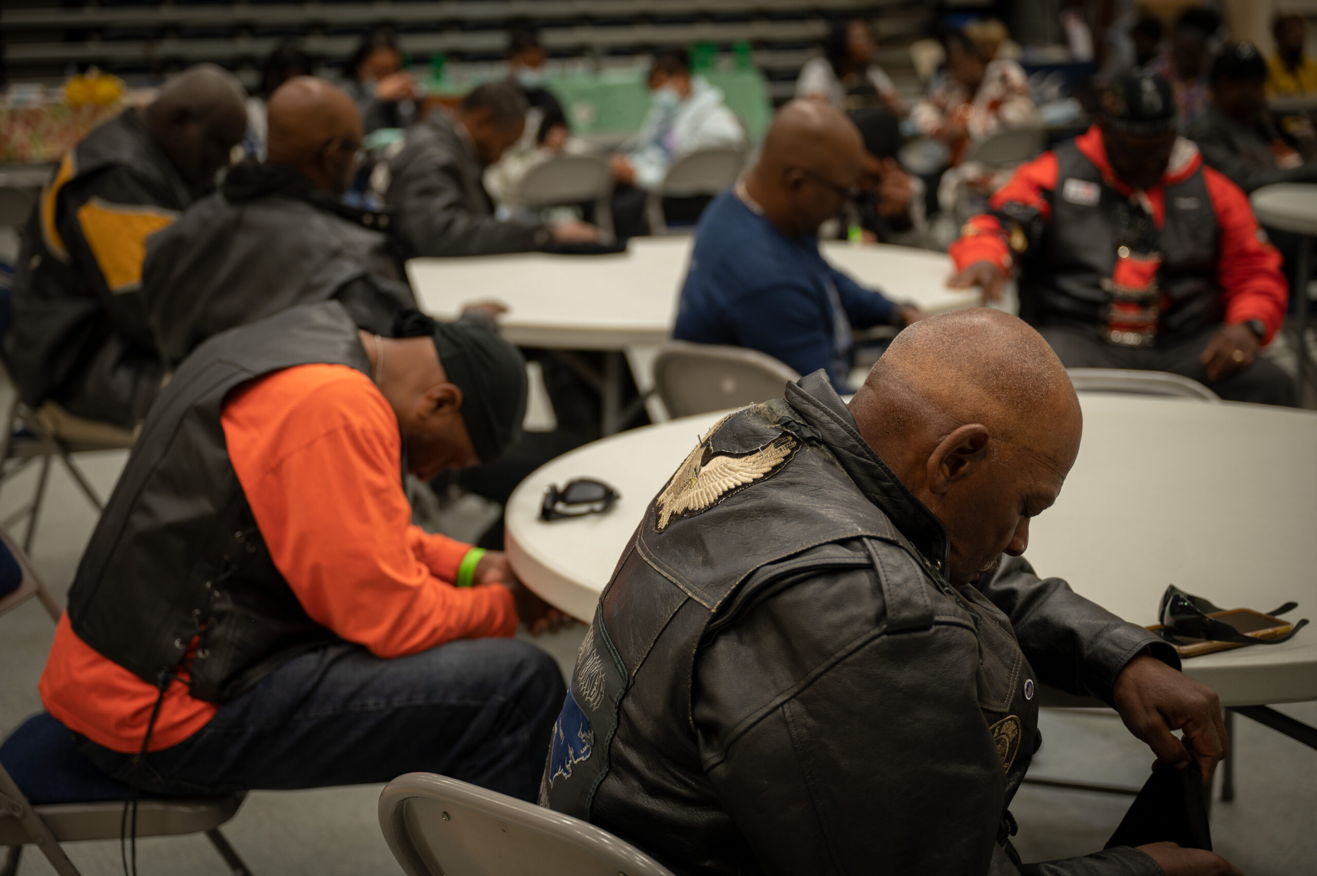 Men sitting around tables bow their heads